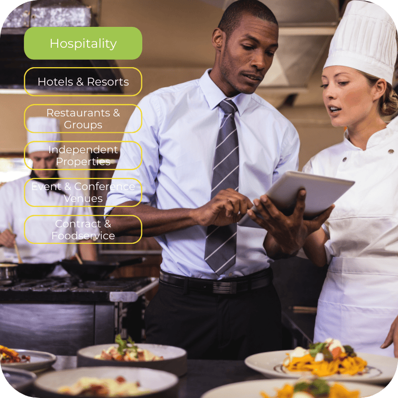 Hospitality manager reviewing digital training on a tablet with chef in a professional kitchen, representing hotels, resorts, restaurant groups, boutique properties, event venues, and contract foodservice operations.